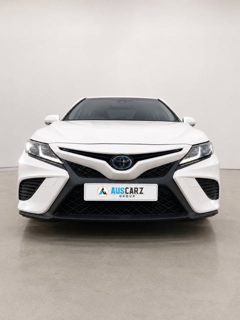 White Toyota Camry sedan photographed head-on in a studio setting with AusCarz Group license plate