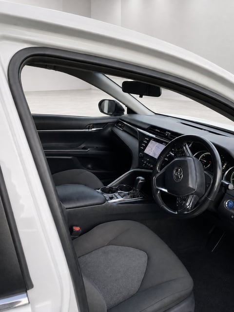 Interior view of white car showing steering wheel, dashboard, and black leather seats