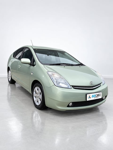 Light green Toyota Prius hybrid car photographed from the side on a white background in a showroom setting