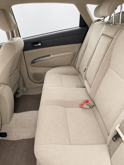 Interior view of car back seat with cream-colored upholstery, windows, and door panel visible