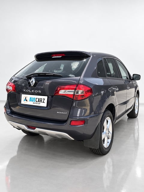 Rear view of a dark blue Renault Koleos SUV with white alloy wheels on a gray studio background