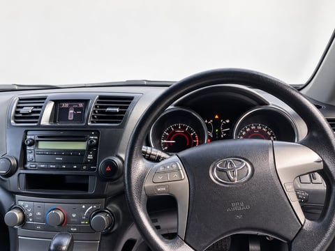 Interior of the Toyota Kluger showing the steering wheel, dashboard, instrument cluster and climate controls