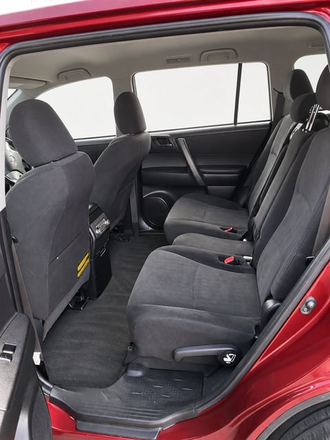 Interior view of the red Toyota Kluger showing black fabric seats, rear door open and clear windows