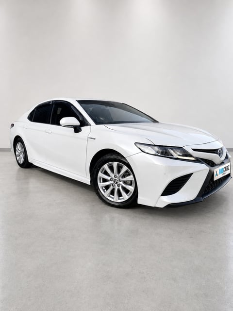White Toyota Camry sedan displayed against a neutral gray background in a studio setting