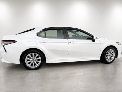 White sedan car photographed from the side view in a studio setting with concrete flooring