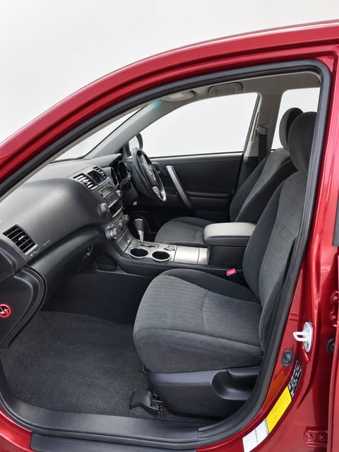 Interior of the red Toyota Kluger showing driver side with black and gray fabric seats, steering wheel and dashboard