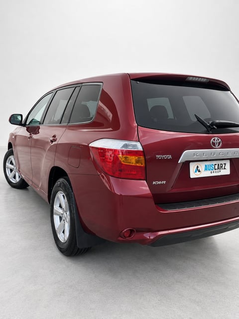 Red Toyota compact SUV photographed from rear three-quarter angle against white background