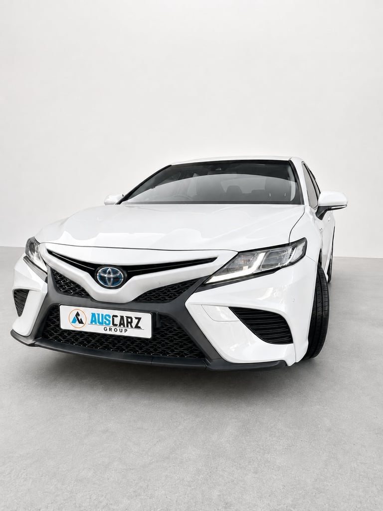 White Toyota Camry sedan with AUS CARZ license plate, front three-quarter view