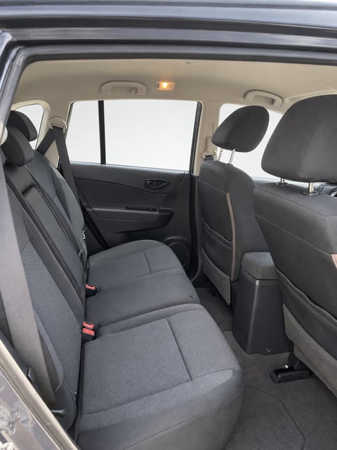 Interior view of car rear seating area with open door, gray fabric seats, and windows visible