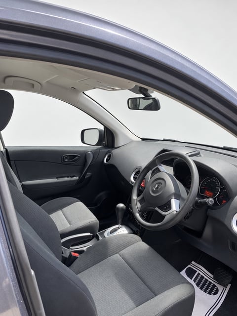 Interior view of a compact car with gray fabric seats, steering wheel, dashboard, and rearview mirror visible through open door